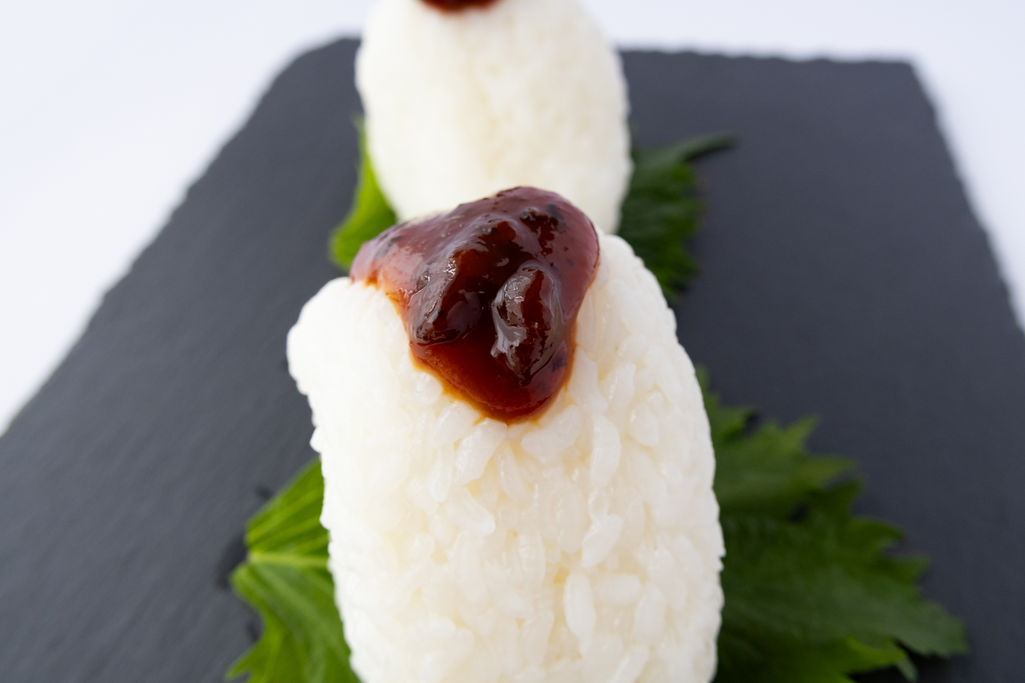 大葉を添えたおにぎりにたこみそをのせた食べ方