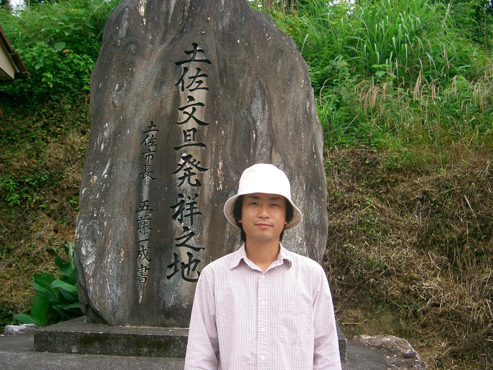 20歳、就農したばかりの園主・矢野弘が、土佐文旦発祥の地の石碑の前に立つ写真